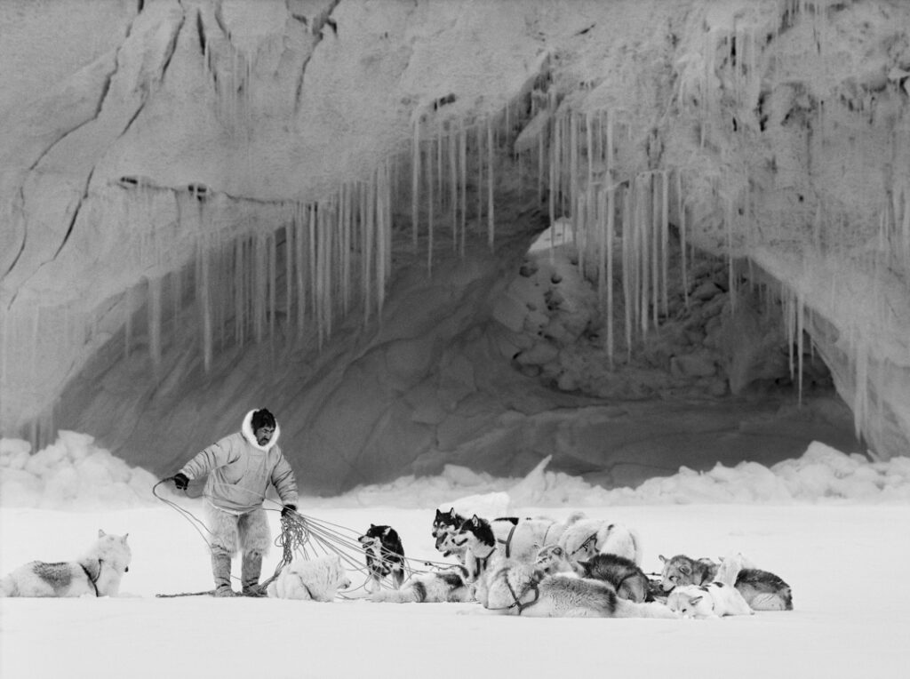 Grönland im Jahr 1999. Ein Inuit mit Schlittenhunden vor Eislandschaft.